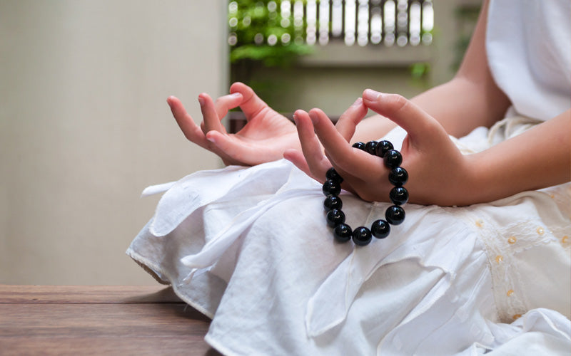 Woman meditating holding a bracelet