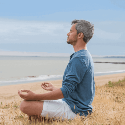 man meditating on the beach